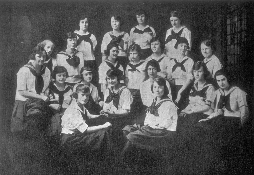 Photographie en noir et blanc d'un groupe de femmes assises au sein d'une équipe de gymnastique
