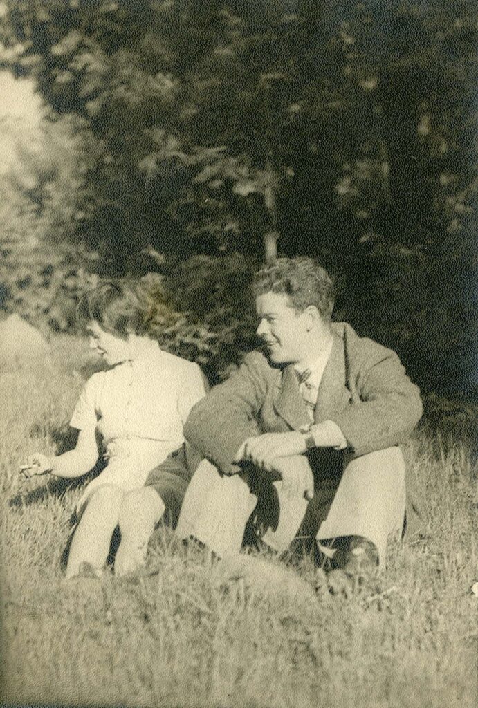 Photographie en noir et blanc d'une femme et d'un homme assis dans l'herbe