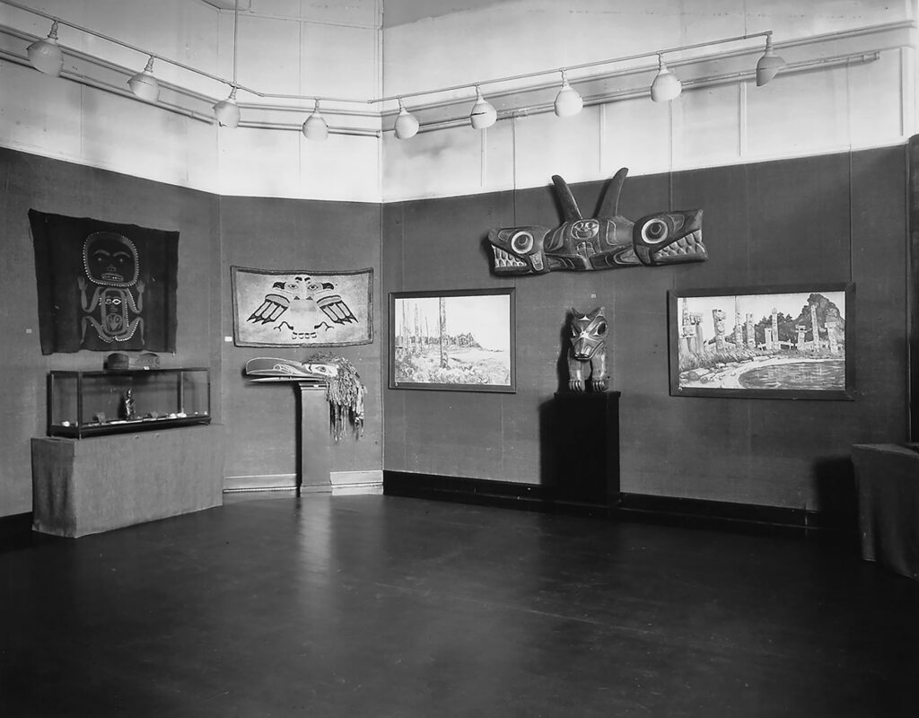 Photographie en noir et blanc d'une pièce abritant diverses pièces artisanales autochtones.