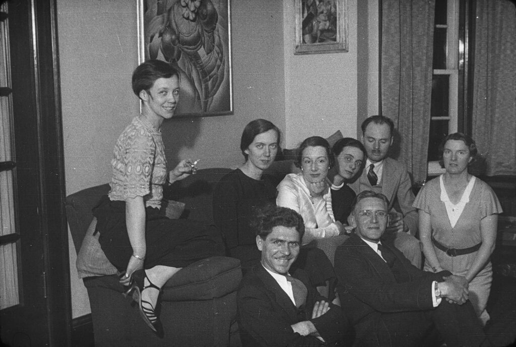 Photographie en noir et blanc d'un groupe de personnes dans une maison