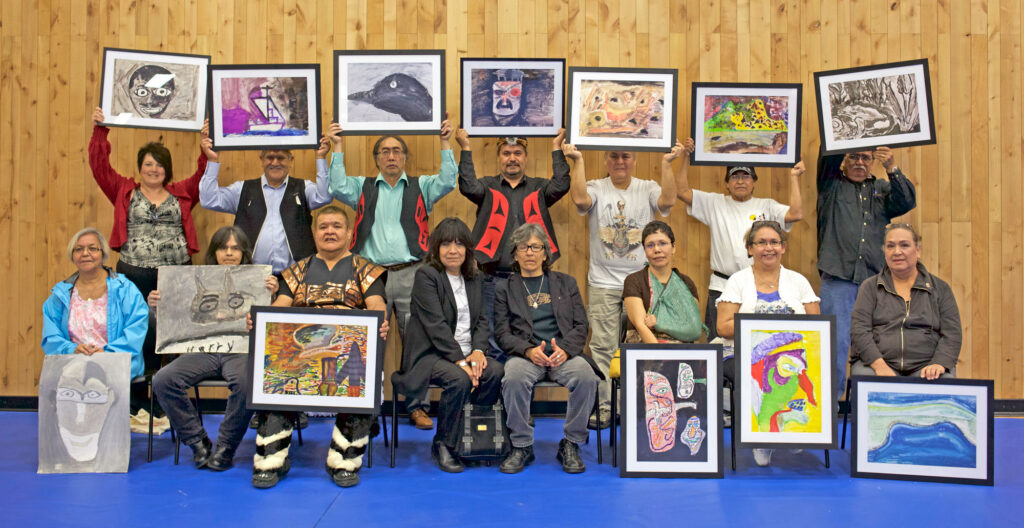 Group of indigenous people holding their framed artworks